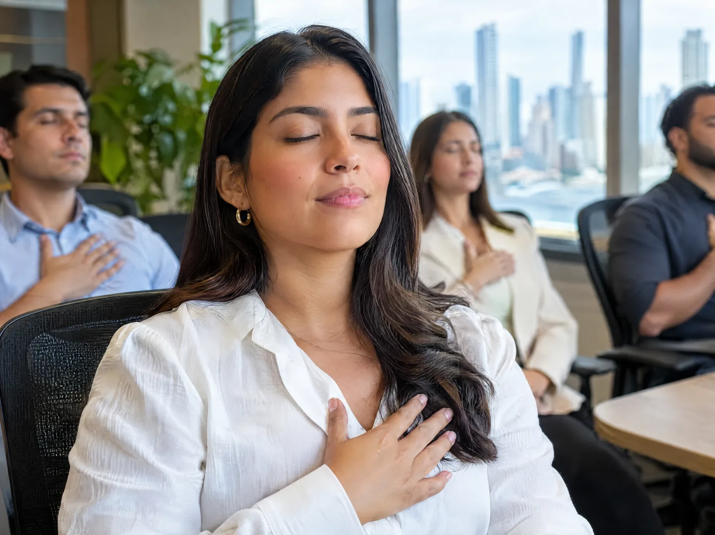 Employee with eyes closed and hand on her chest during a breathing practice at the office