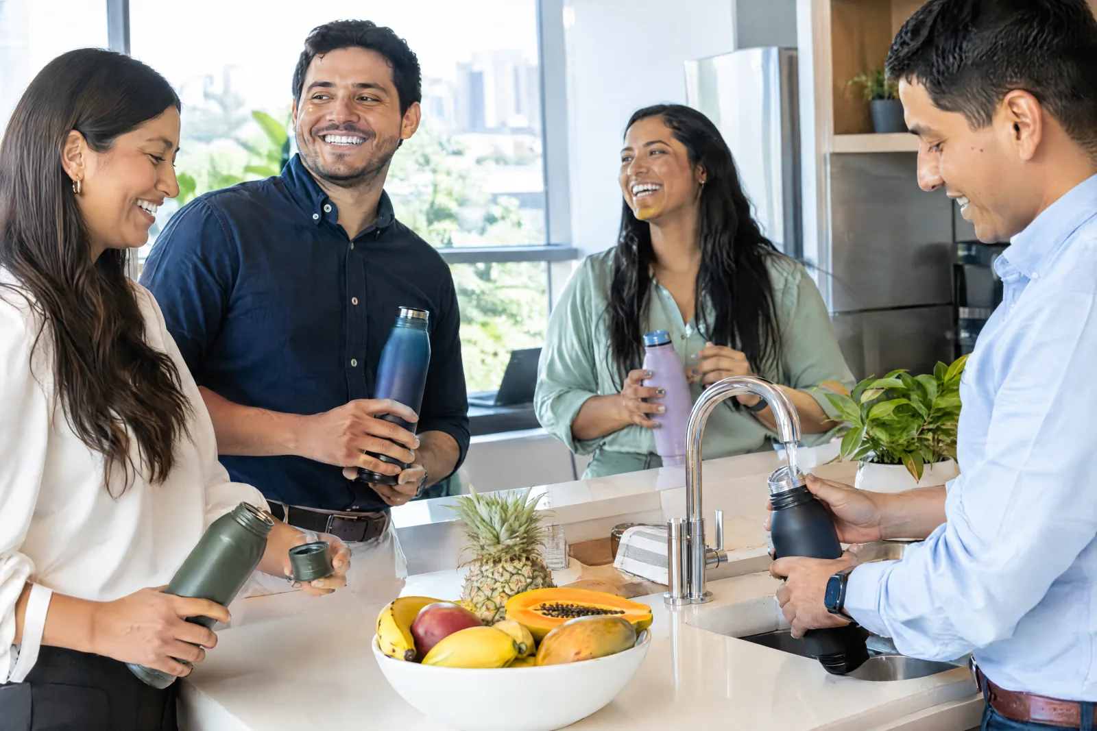 Coworkers laughing while refilling their water bottles