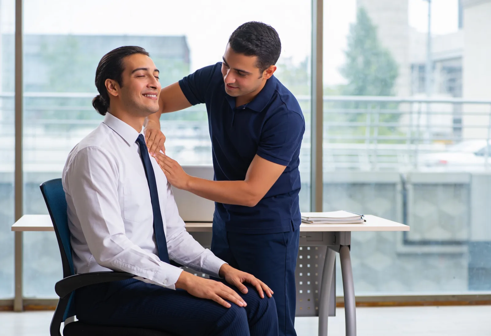 THA professional giving a chair massage to an employee by the window